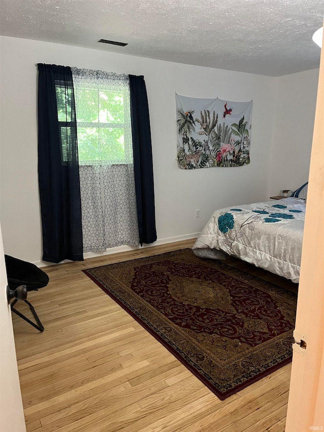 bedroom featuring a textured ceiling and hardwood / wood-style floors