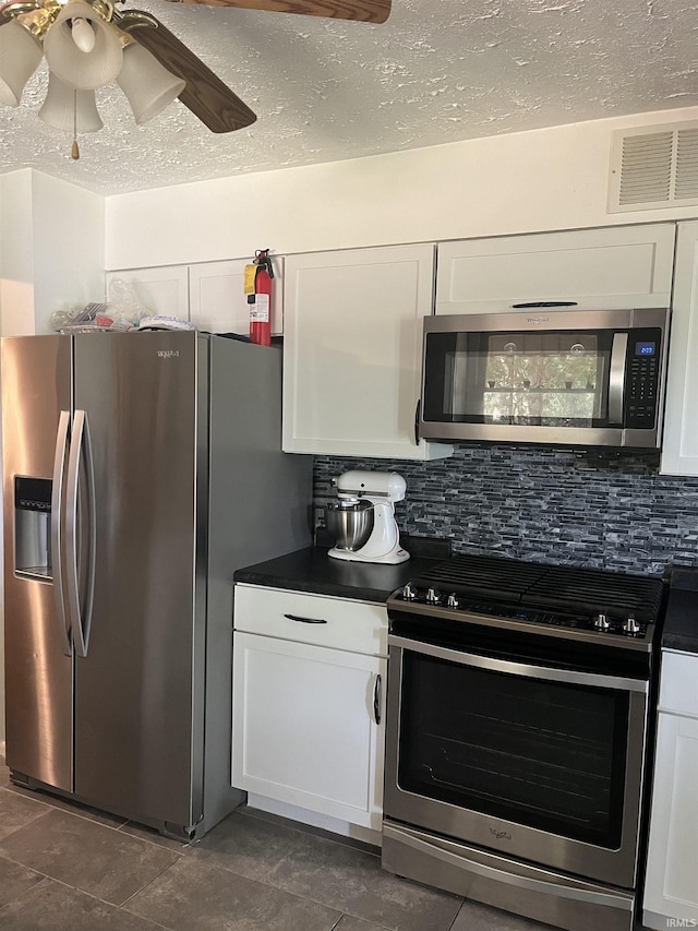 kitchen with ceiling fan, stainless steel appliances, backsplash, a textured ceiling, and white cabinets