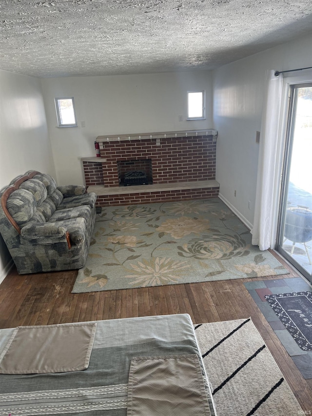 living room with a brick fireplace, a textured ceiling, and hardwood / wood-style flooring