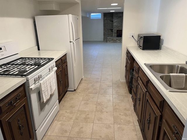 kitchen with gas range gas stove, dark brown cabinetry, and sink