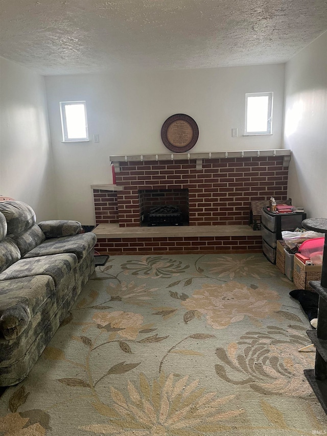 living room featuring a textured ceiling, a brick fireplace, and a healthy amount of sunlight