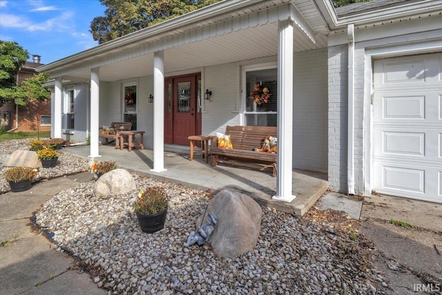 view of exterior entry featuring a garage and a porch