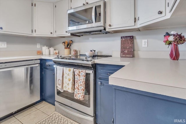 kitchen featuring appliances with stainless steel finishes, blue cabinetry, white cabinets, and light tile patterned floors