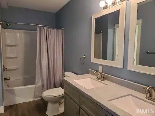 full bathroom featuring shower / bath combo, hardwood / wood-style floors, vanity, and toilet