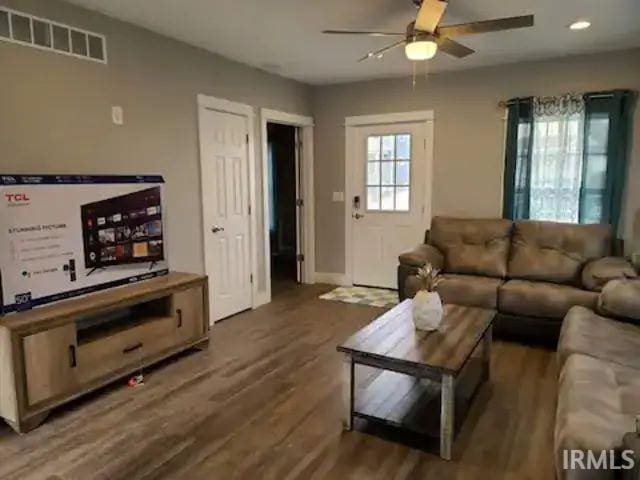 living room featuring ceiling fan and dark wood-type flooring