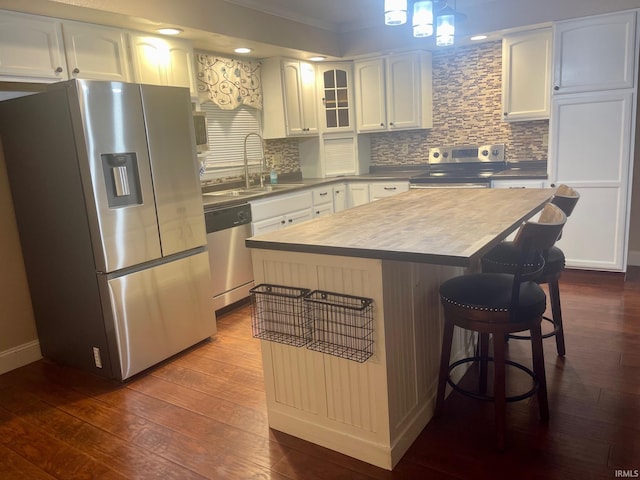 kitchen with dark wood-type flooring, sink, white cabinetry, a kitchen island, and stainless steel appliances