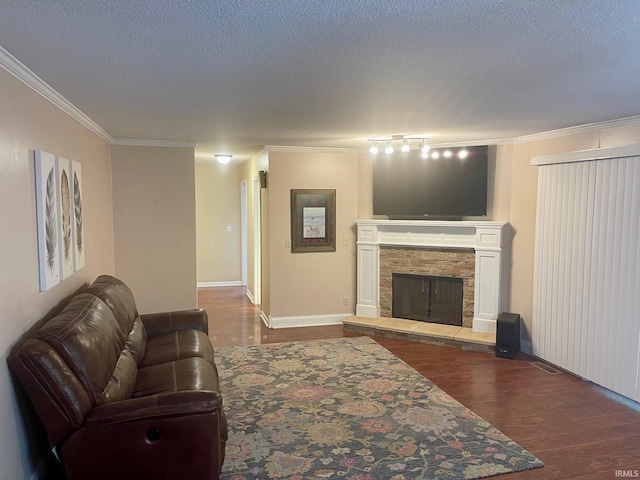 living room with a stone fireplace, ornamental molding, hardwood / wood-style floors, and a textured ceiling