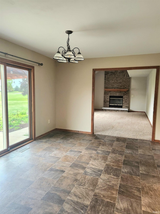 unfurnished living room with an inviting chandelier, dark colored carpet, and a brick fireplace