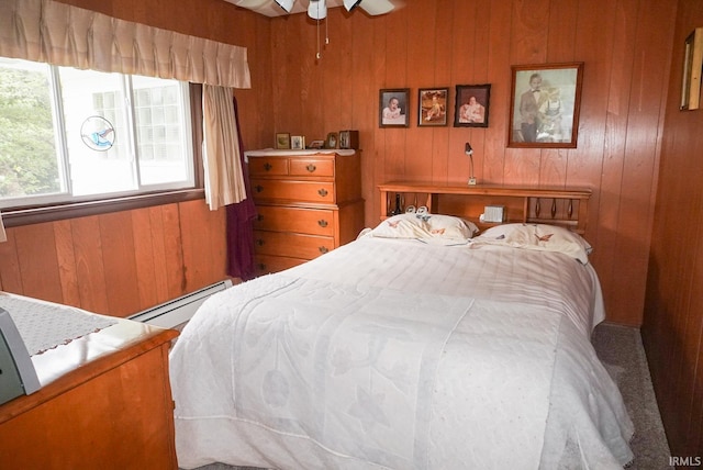 bedroom featuring wooden walls and a baseboard heating unit