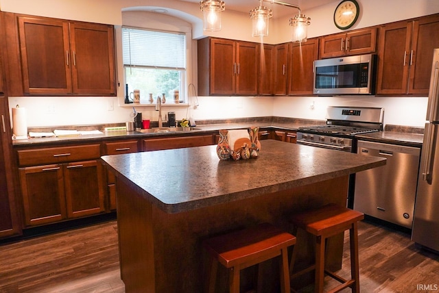 kitchen with dark hardwood / wood-style floors, a kitchen island, sink, and stainless steel appliances