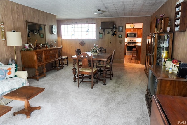 dining area with light carpet and wood walls