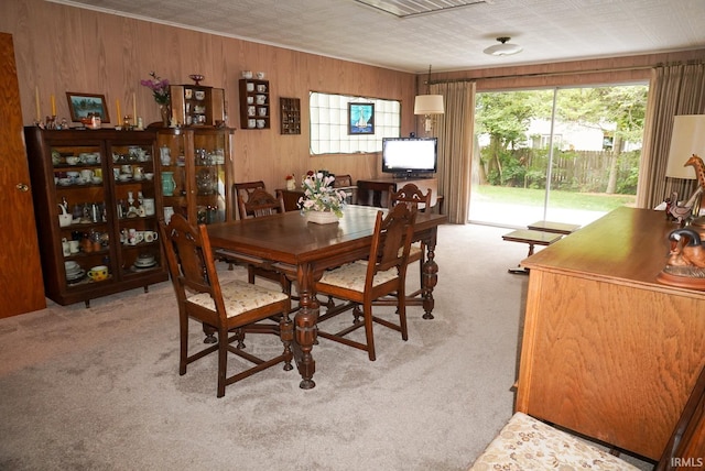 carpeted dining area featuring wooden walls