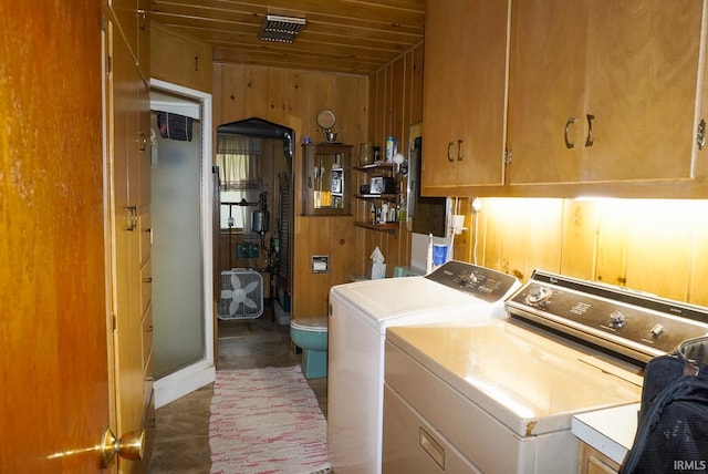 laundry room with wooden ceiling, cabinets, wooden walls, electric panel, and washer and dryer