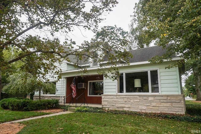 view of front of home with a front lawn and an AC wall unit