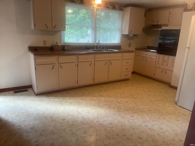 kitchen featuring black oven, a textured ceiling, cream cabinets, and sink