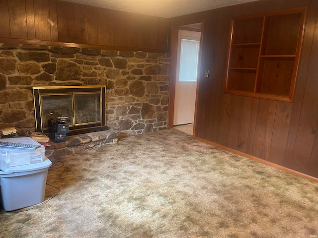 unfurnished living room featuring wooden walls, a fireplace, carpet flooring, and a textured ceiling