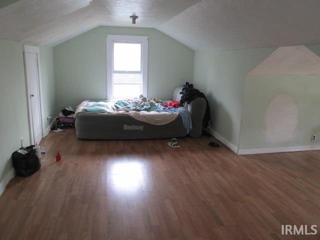 bedroom featuring vaulted ceiling, a textured ceiling, and dark hardwood / wood-style flooring