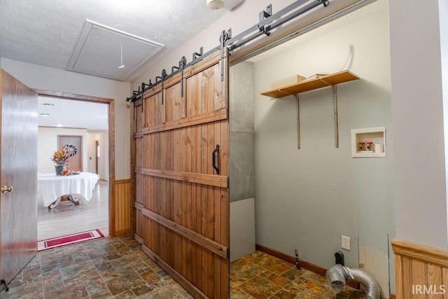 interior space with washer hookup, a textured ceiling, wood walls, and a barn door