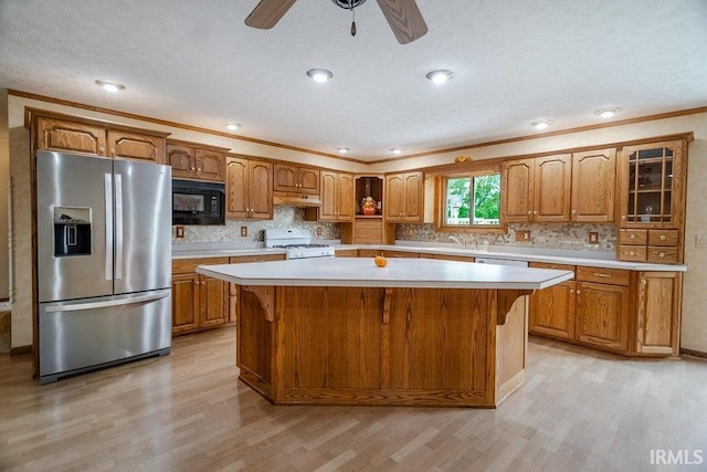 kitchen with ceiling fan, stainless steel fridge, white gas range, a center island, and light wood-type flooring