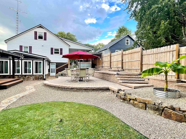 back of property featuring a deck, a lawn, and a patio area