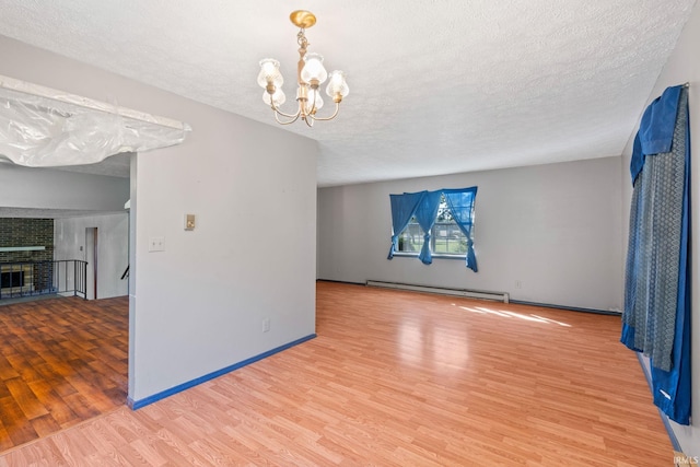 unfurnished room with a notable chandelier, a baseboard radiator, hardwood / wood-style floors, and a textured ceiling