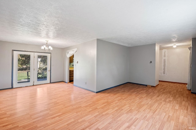 unfurnished room with a chandelier, light hardwood / wood-style flooring, and a textured ceiling