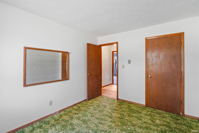 spare room featuring a textured ceiling and light colored carpet