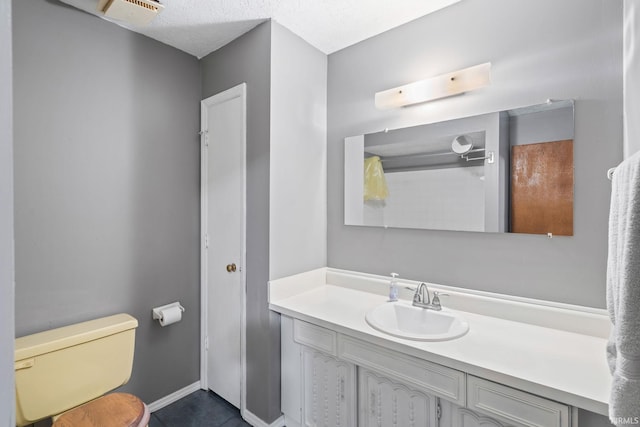 bathroom with vanity, toilet, and a textured ceiling