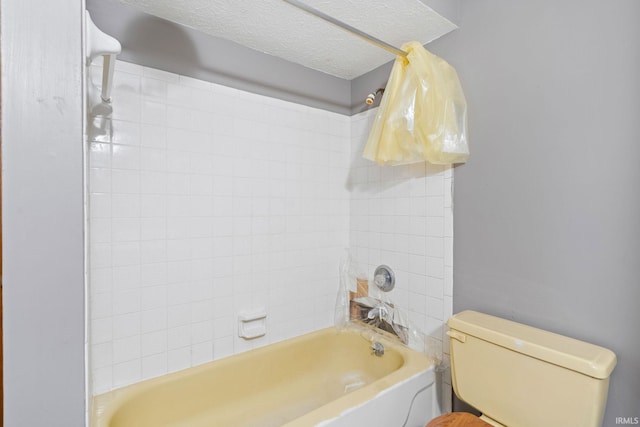 bathroom featuring tiled shower / bath combo, a textured ceiling, and toilet