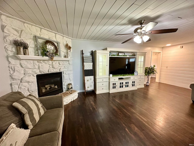 living room with ceiling fan, a fireplace, dark hardwood / wood-style floors, and wooden ceiling