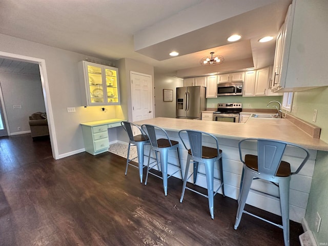 kitchen featuring sink, white cabinetry, stainless steel appliances, dark hardwood / wood-style floors, and a kitchen breakfast bar