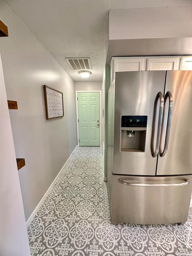 kitchen featuring white cabinets, stainless steel refrigerator with ice dispenser, and a textured ceiling