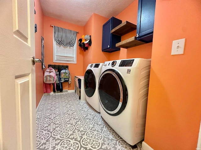 laundry area with washer and clothes dryer, cabinets, and a textured ceiling