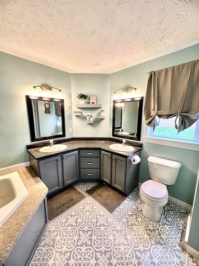 bathroom with a textured ceiling, a bathtub, vanity, and toilet