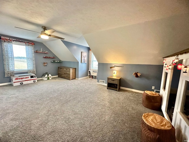 interior space featuring ceiling fan, carpet flooring, a textured ceiling, and vaulted ceiling