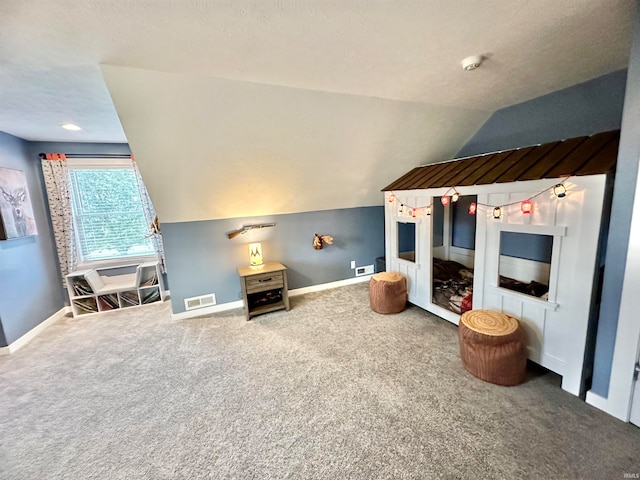 interior space with a textured ceiling, carpet flooring, and vaulted ceiling