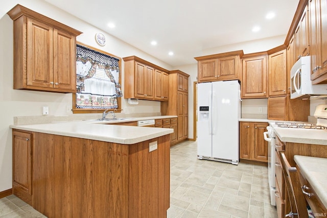 kitchen with white appliances, kitchen peninsula, and sink