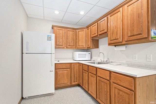 kitchen with white appliances, sink, and a drop ceiling