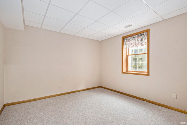 unfurnished room featuring carpet flooring and a drop ceiling