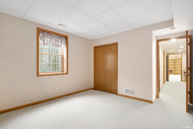 empty room featuring carpet and a paneled ceiling