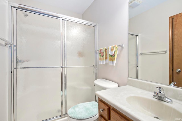 bathroom featuring a shower with door, vanity, and toilet