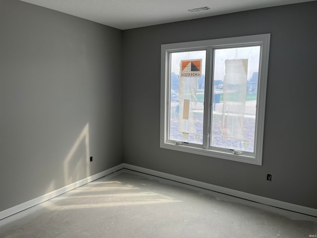 unfurnished room with a textured ceiling, concrete floors, and a wealth of natural light