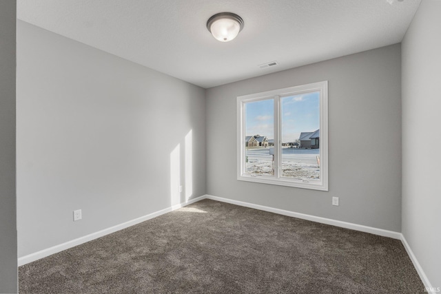 unfurnished room featuring a textured ceiling and dark colored carpet