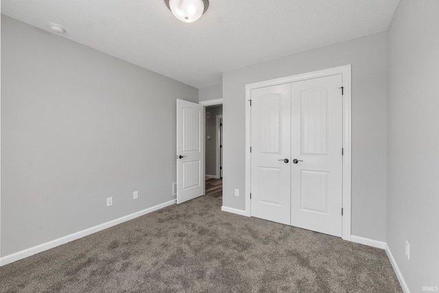 unfurnished bedroom featuring dark colored carpet and a closet