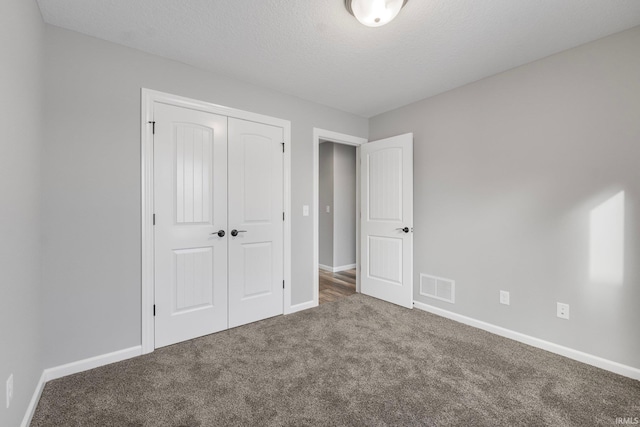 unfurnished bedroom with carpet, a textured ceiling, and a closet