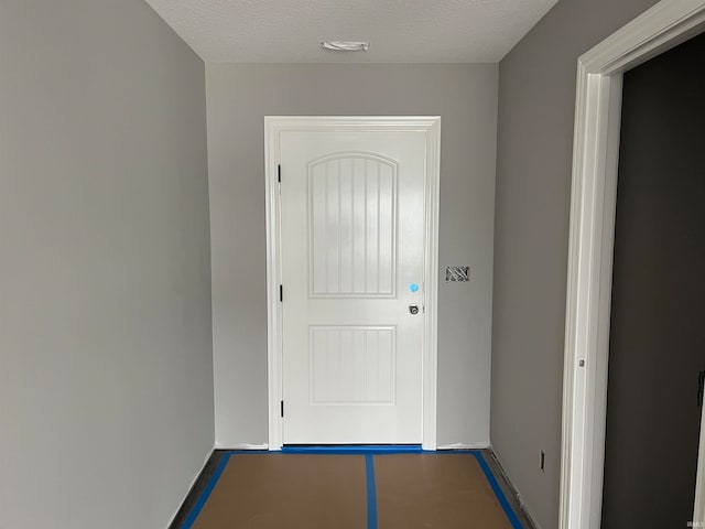 doorway to outside featuring a textured ceiling