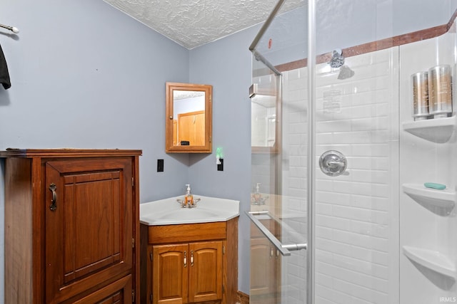 bathroom with vanity, a textured ceiling, and a shower with door