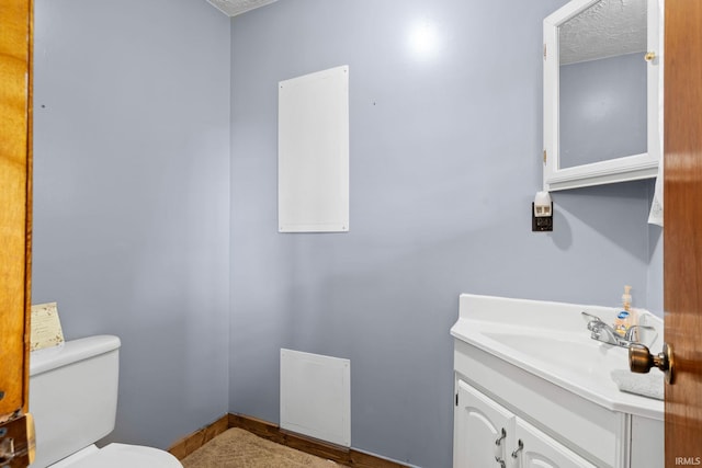 bathroom with a textured ceiling, vanity, and toilet