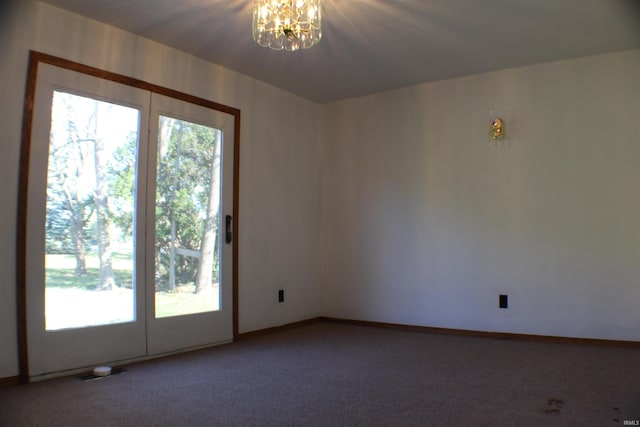 carpeted spare room featuring a notable chandelier