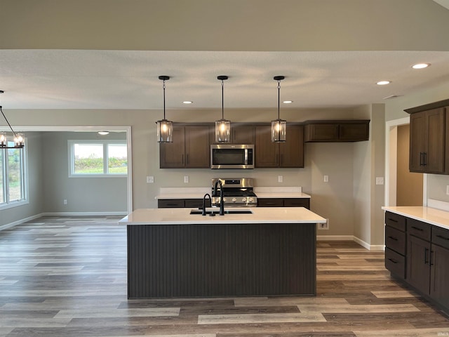 kitchen featuring a kitchen island with sink, hanging light fixtures, and appliances with stainless steel finishes